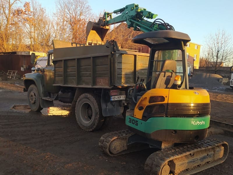 Мініекскаватор Kubota вантажить ґрунт у самоскид ЗІЛ