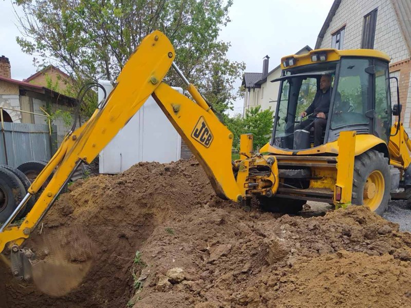 Екскаватор JCB з нашим водієм копає яму біля приватного будинку